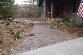 Cobblestone paver entrance walk with natural stone step and boulder accents.