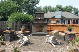 Paver patio, built-in bench seats, pillars, and stone fireplace.