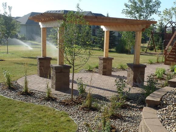 Cedar pergola, overhead, arbor with stone pillars or columns and a paver patio.